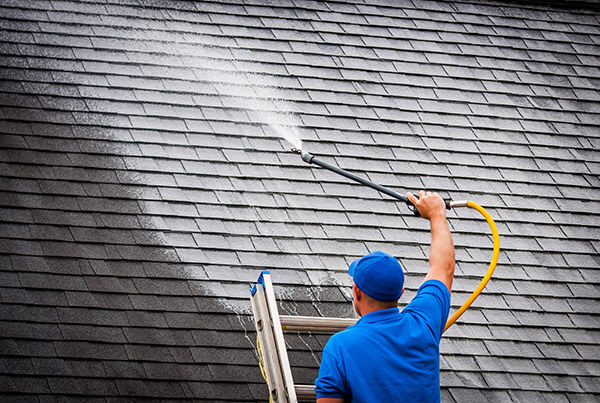 Close-up of a roof being rinsed clean with a soft wash wand