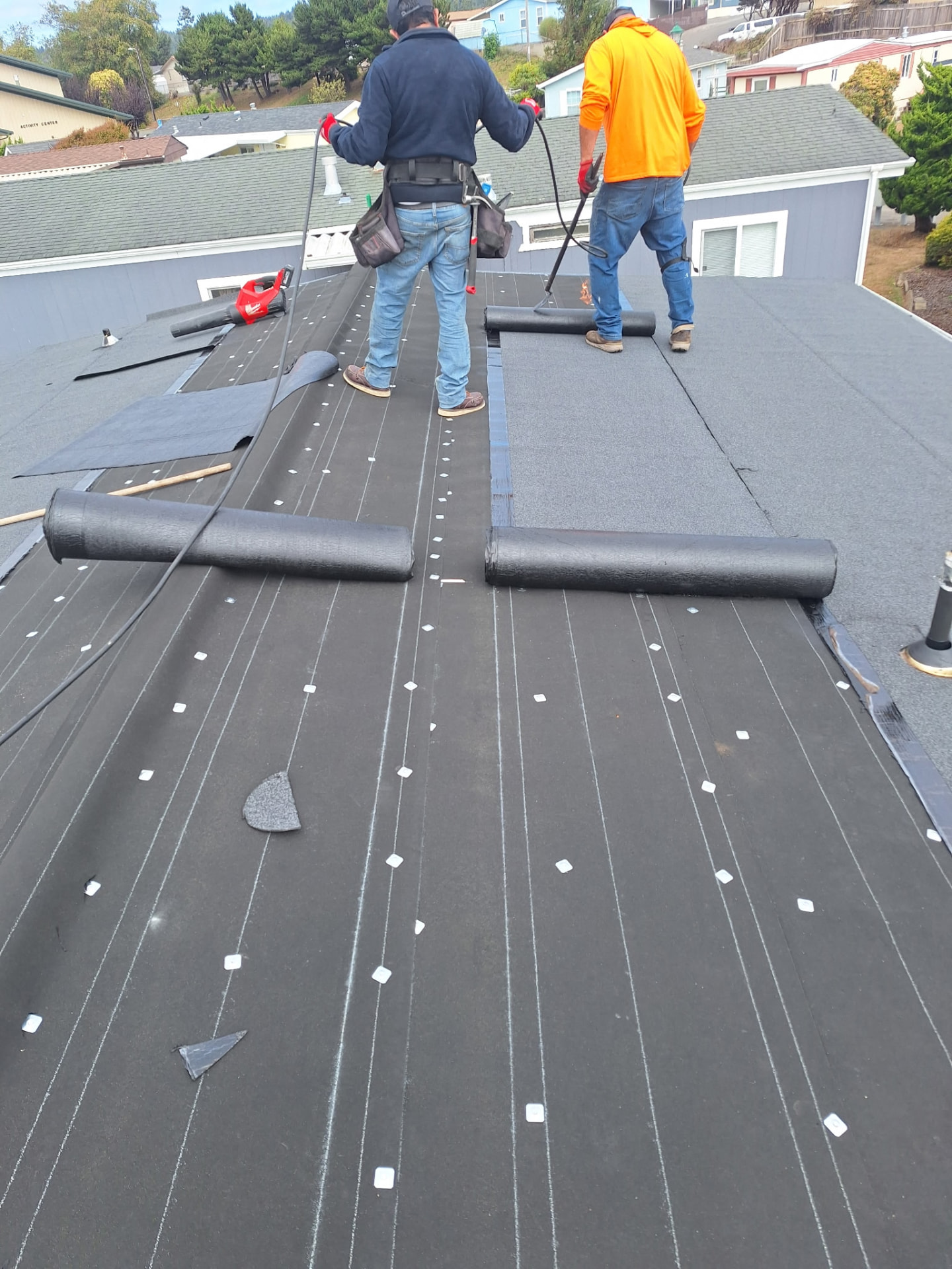 Roll-Out — The new roofing material is rolled out across the roof.